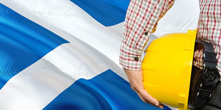 Scottish Engineer is holding yellow safety helmet with waving Sc